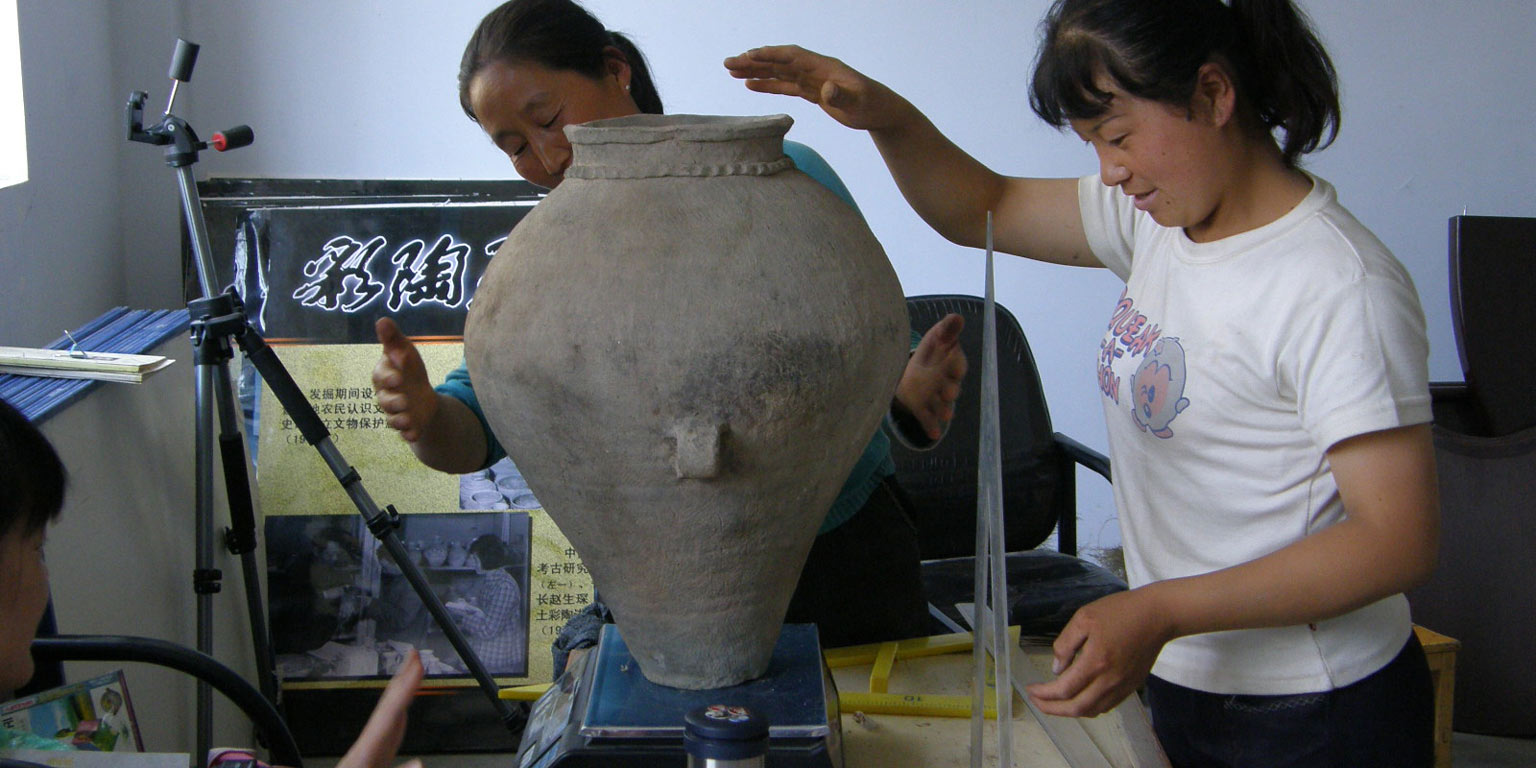 Two women working with a large pot