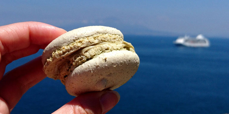 A hand holding food with a sea in the background