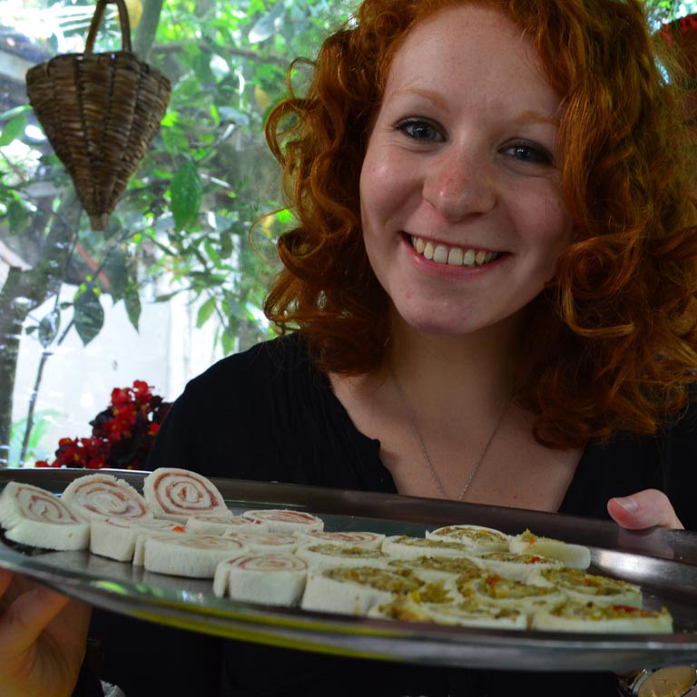 A woman smiling and carrying a tray of food samples