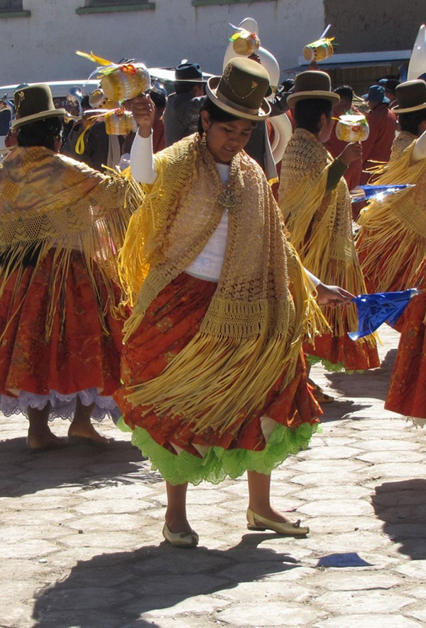 A picture of a dancer at a festival in Bolivia, who wears traditional Bolivian attire and is dancing outside.