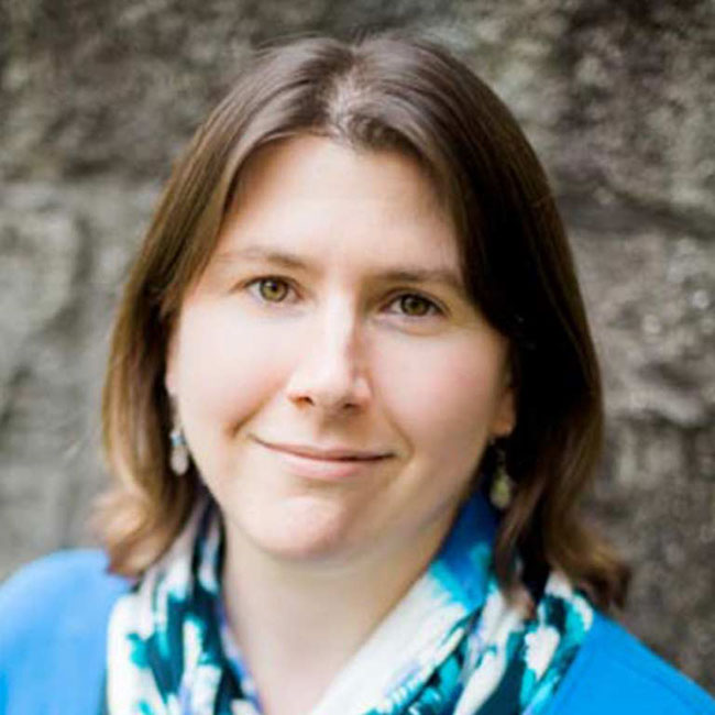 A headshot of advisor Kristen Murphy, who poses against a stone wall and wears a blue shirt.