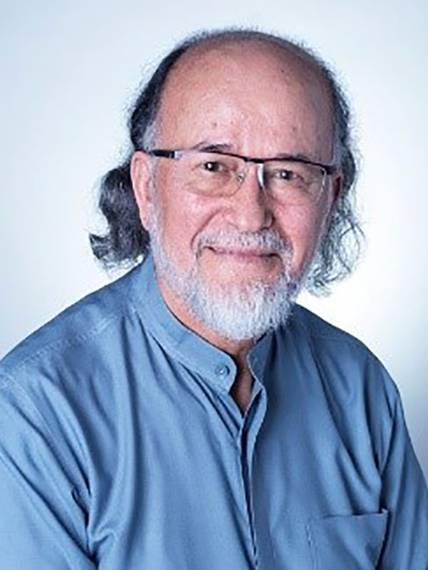 A headshot of Professor Nazif Mohib Shahrani, who wears a blue dress shirt and poses against a blue background.