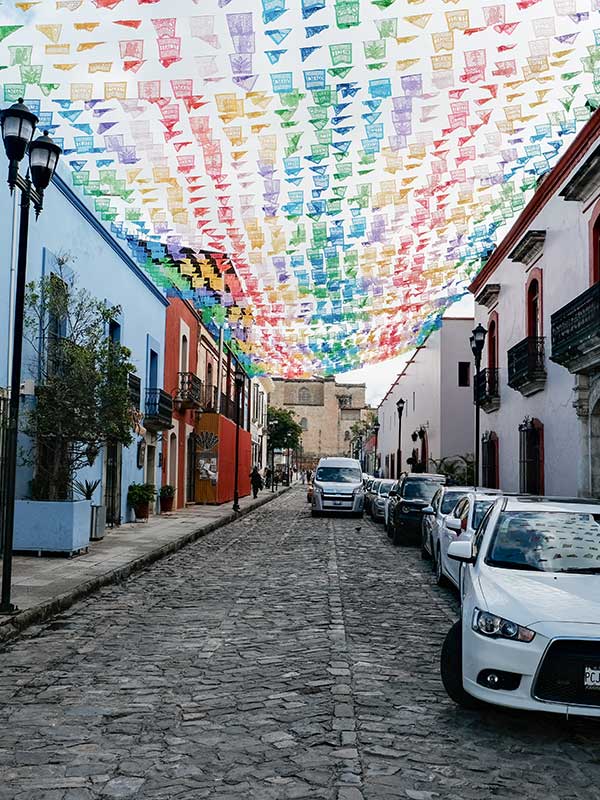A street in Oaxaca with colorful banners crossing over it. Picture taken by Francisco Anzola.