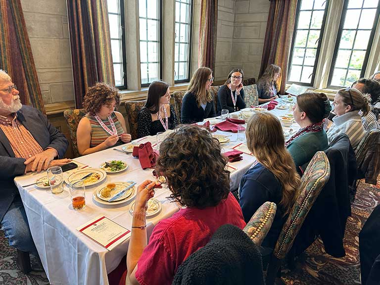 People eat together at a table in the Tudor Room.