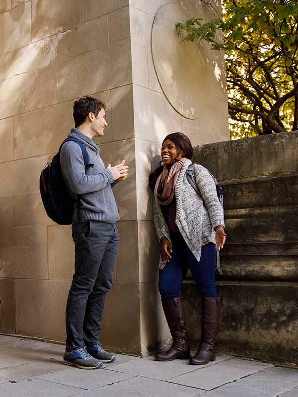 Two students talk outside of an academic building on IU's campus.
